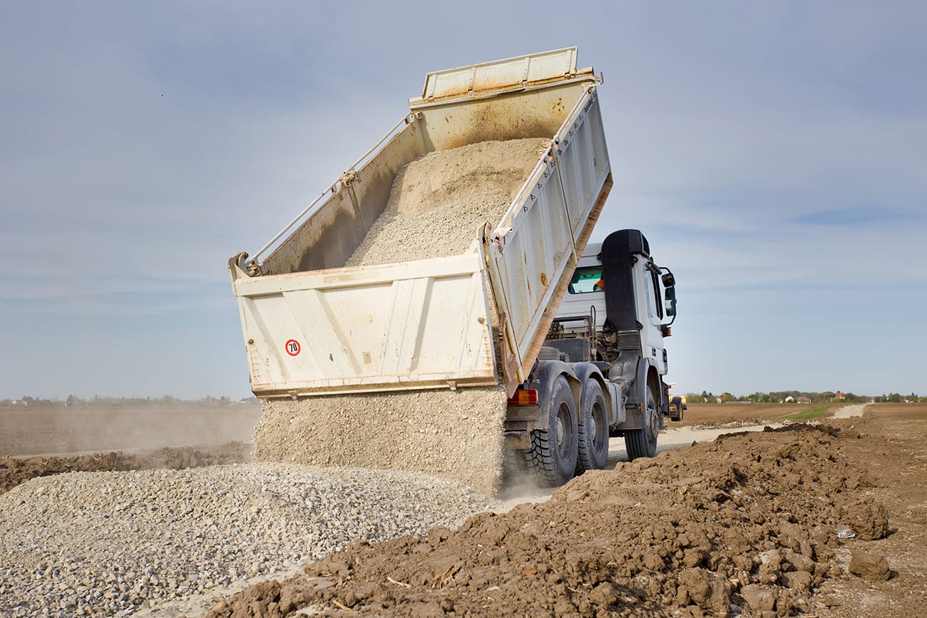 Tipping-truck-unloading-gravel-on-road-construction-site Tipping truck unloading gravel on road construction site